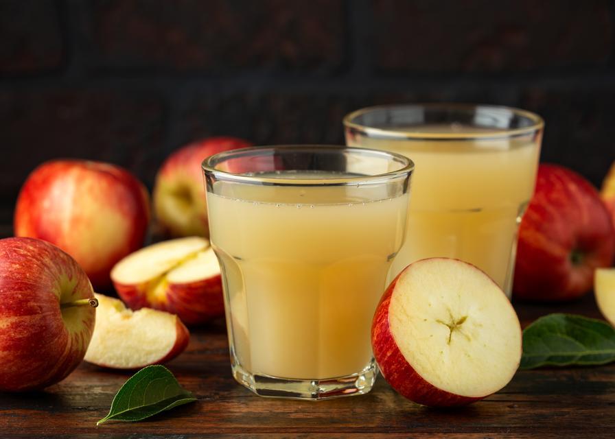 Apple juice in glass on rustic wooden table.