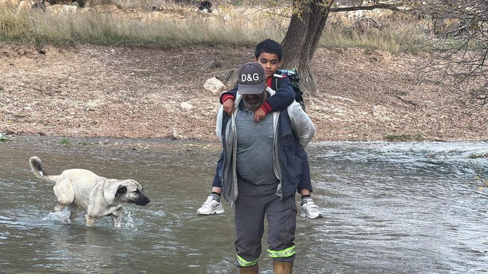 Köprü yıkılınca evladını her gün sırtında taşıyıp ırmaktan geçiriyor